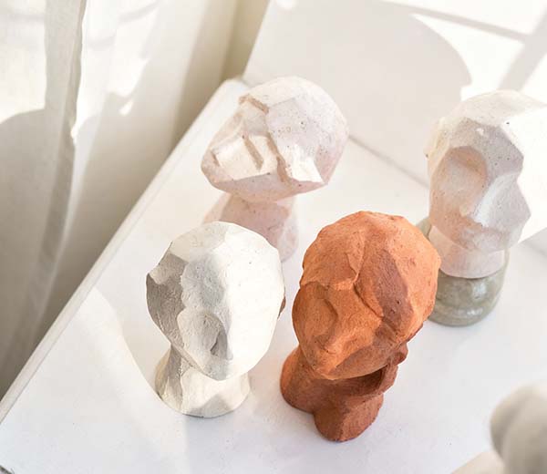Abstract bust sculptures in white and terracotta colors on a white surface.
