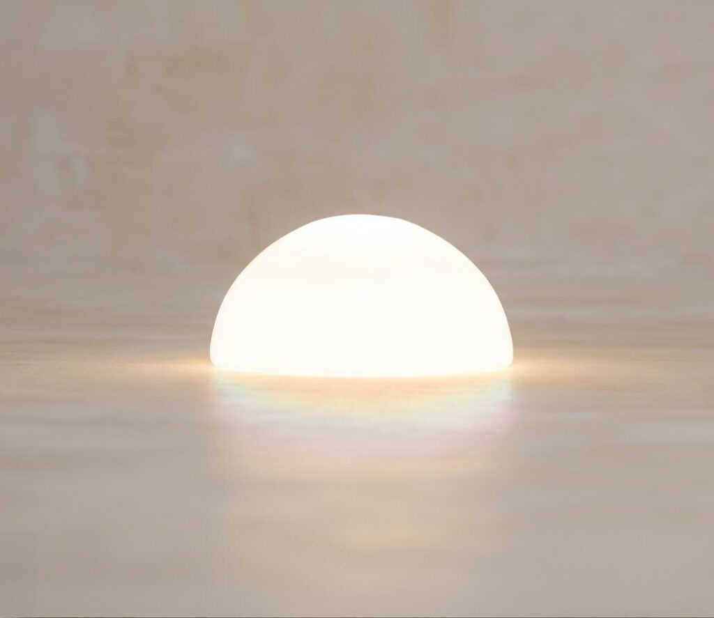 A bright white orb glowing softly on a reflective surface.